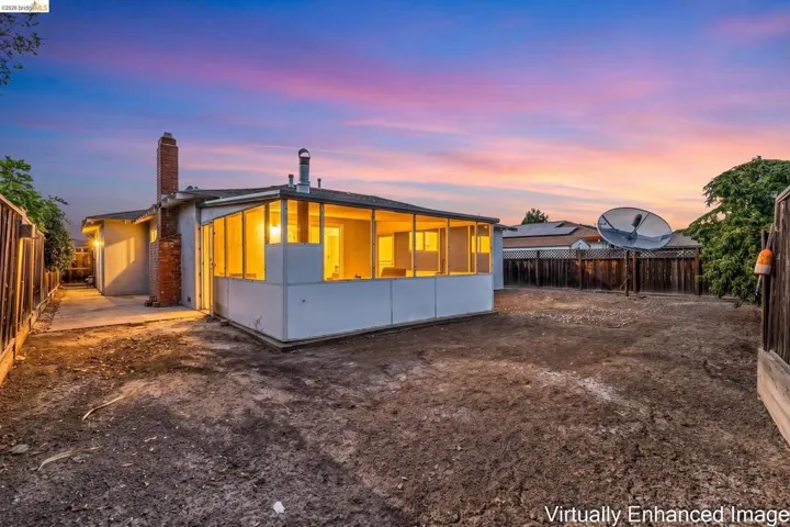 Spacious rear yard featuring a screened-in patio, brick chimney, and concrete walkway