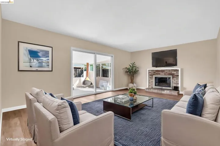 Living area with wood-finish flooring, a brick-surround fireplace, and expansive sliding glass doors