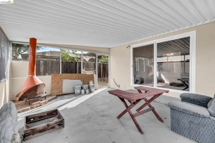 Covered patio area featuring a concrete slab, a built-in outdoor fireplace, and sliding glass doors