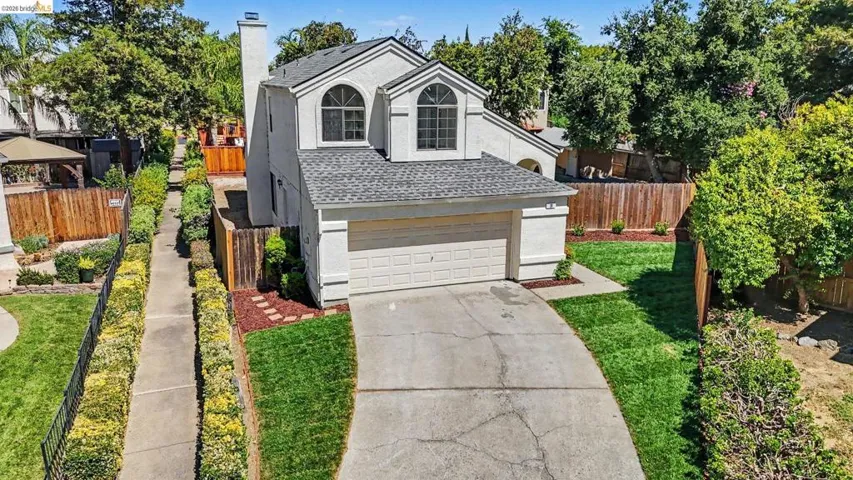 Two-story stucco residence featuring a two-car garage, arched windows, and a prominent chimney