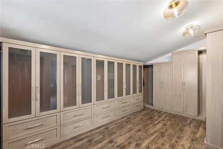 Huge primary walk in closet with custom cabinets and flooring