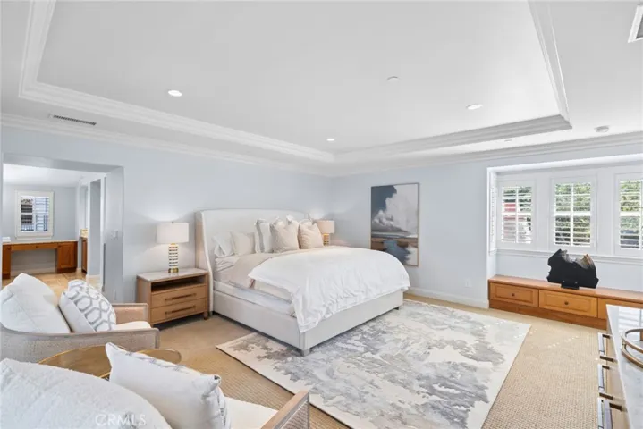 The primary suite offers a sitting area, viewing deck, elegant tray ceiling w/ crown molding, oversized custom walk-in closet & spa-inspired bath w/dual vanities, soaking tub, frameless glass shower & refined finishes