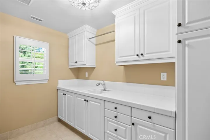 upstairs laundry room with utility sink and custom cabinetry
