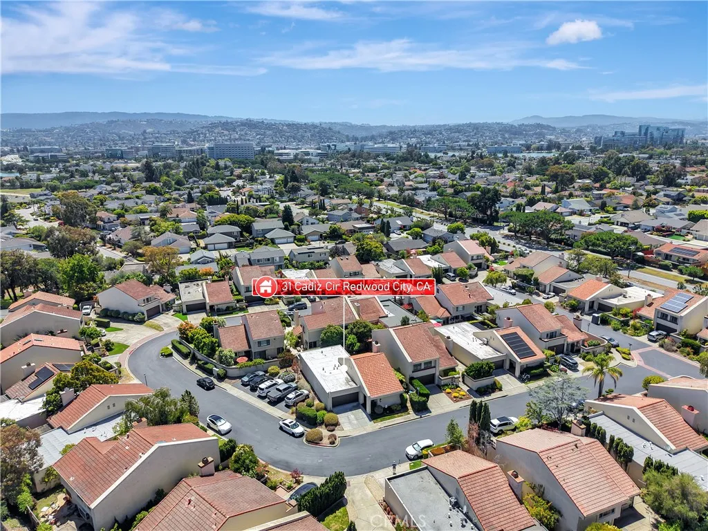 Expansive aerial view capturing the neighborhood setting with scenic city and hillside views in the distance.