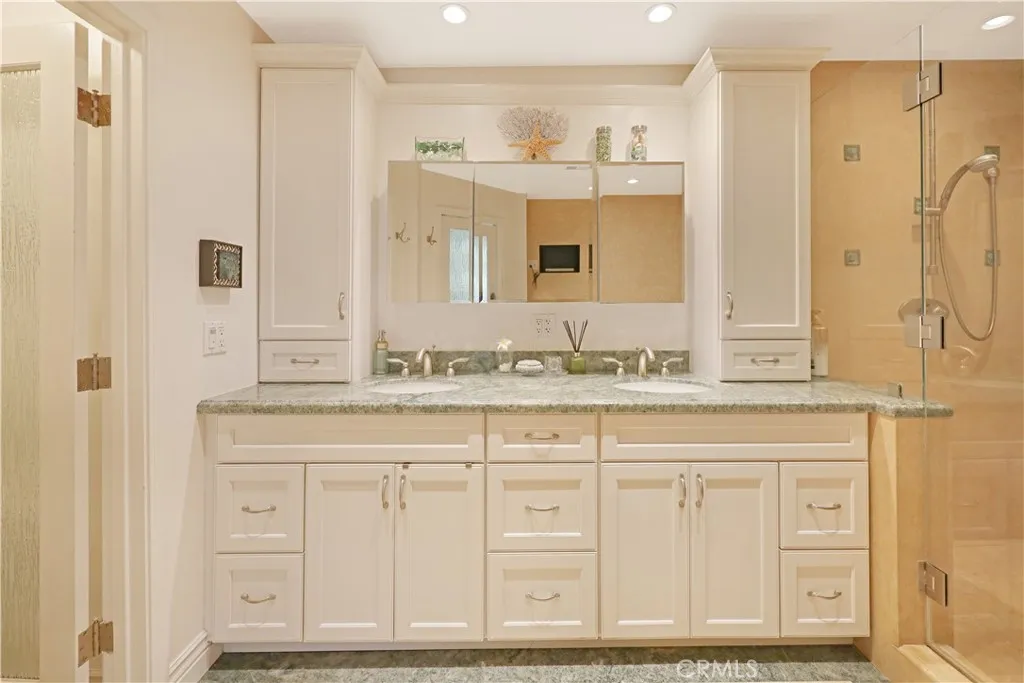 Bathroom featuring an extended vanity with abundant storage and a large mirror.