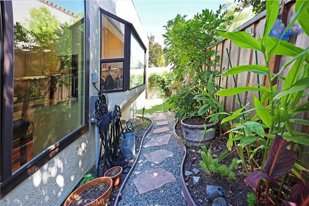 Private courtyard-style walkway enhanced by mature tropical landscaping and colorful planting beds.