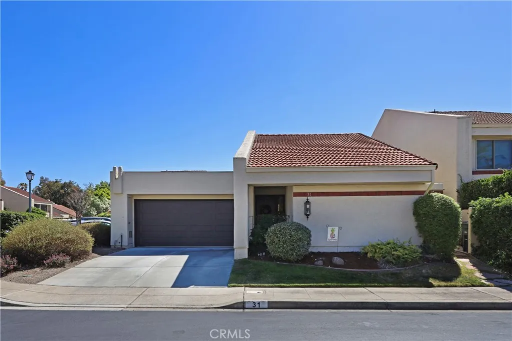 Wide front elevation displaying the home's attractive façade, mature landscaping, and convenient two-car garage.
