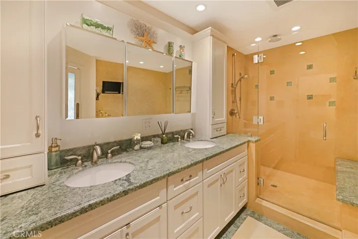 Spacious bathroom with dual sinks, expansive counter space, and warm finishes