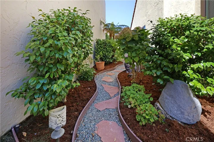 Charming garden walkway surrounded by mature landscaping that creates a peaceful outdoor setting.