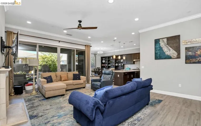 Spacious living area featuring wood-finish flooring, recessed lighting, and crown molding