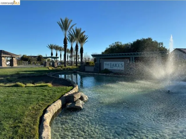 Decorative water feature with a stone perimeter and fountain, surrounded by manicured green space