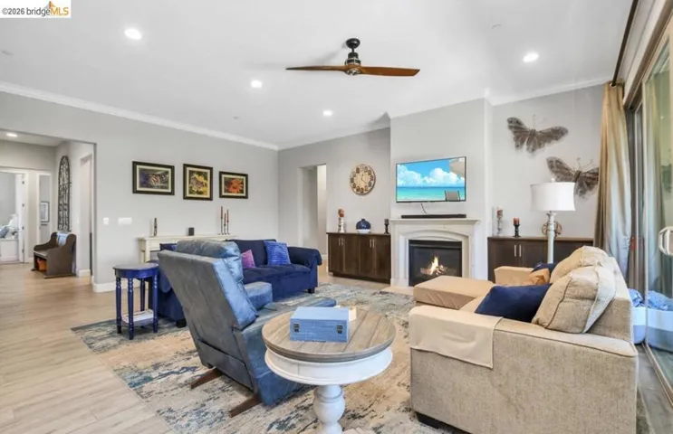 Spacious living area featuring wood-finish flooring, a fireplace with a mantel, recessed lighting, and a ceiling fan