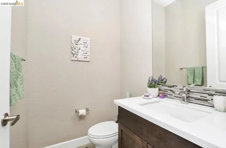 Powder room featuring a white single-sink vanity with dark wood-finish cabinetry, a contemporary chrome faucet, and a horizontally-stacked tile backsplash