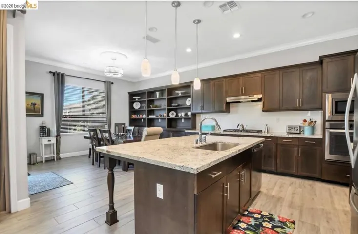 Kitchen island with granite countertop and double-basin sink, complemented by pendant lighting