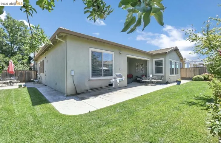 Rear exterior featuring a covered patio, multiple windows, and a concrete walkway