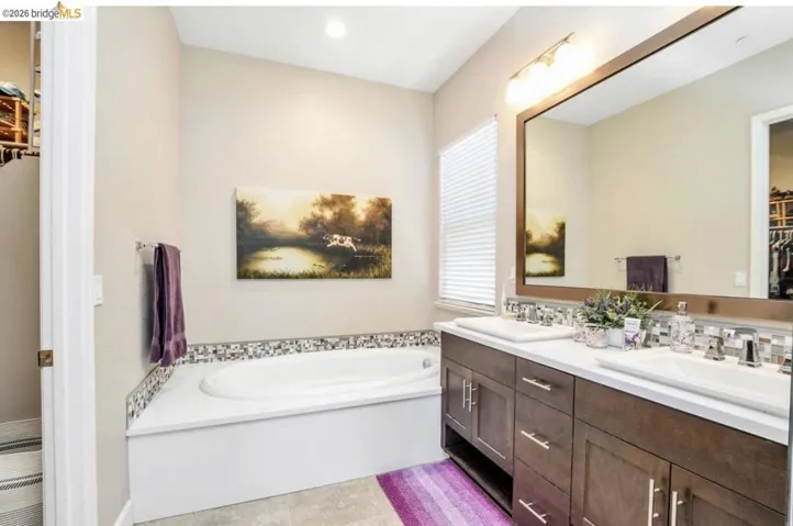 Dual vanity with undermount sinks, bronze wood-finish cabinetry, and a large framed mirror