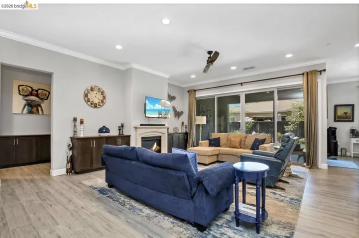 Spacious living area featuring wood-finish flooring, recessed lighting, and crown molding