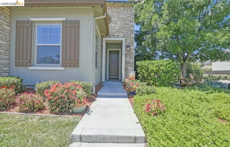 Stucco and stone exterior featuring decorative window shutters and a paneled entry door