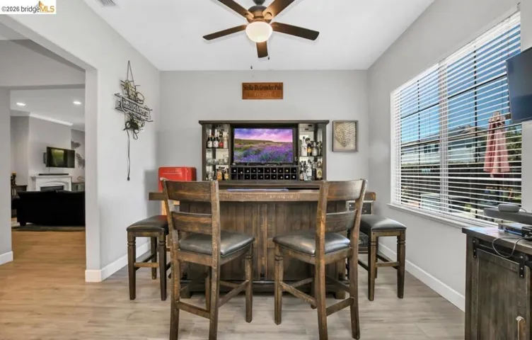 Dedicated entertainment area featuring wood-finish flooring and a built-in bar with integrated shelving