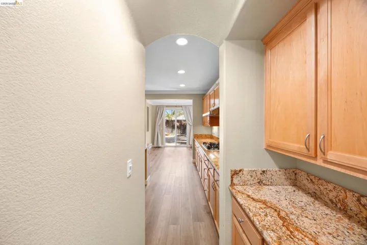 Galley kitchen featuring wood-finish cabinetry, patterned countertops, and recessed lighting