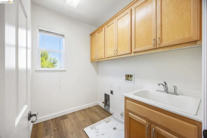 Utility space featuring a window, wood-finish flooring, built-in cabinetry, and a utility sink
