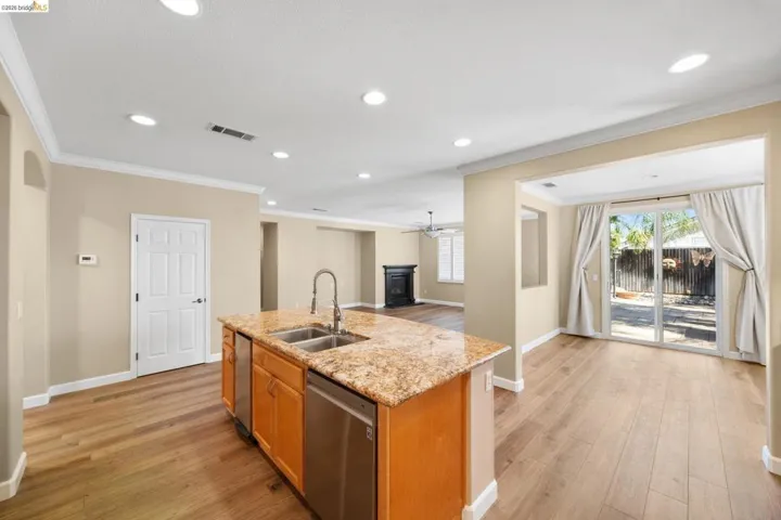 Kitchen island featuring a double-basin sink, gooseneck faucet, and integrated stainless steel dishwasher