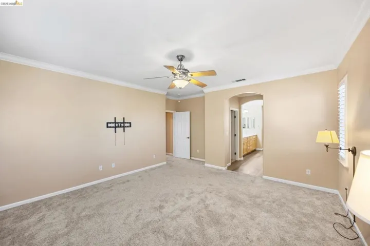 Spacious room featuring neutral carpeting and crown molding