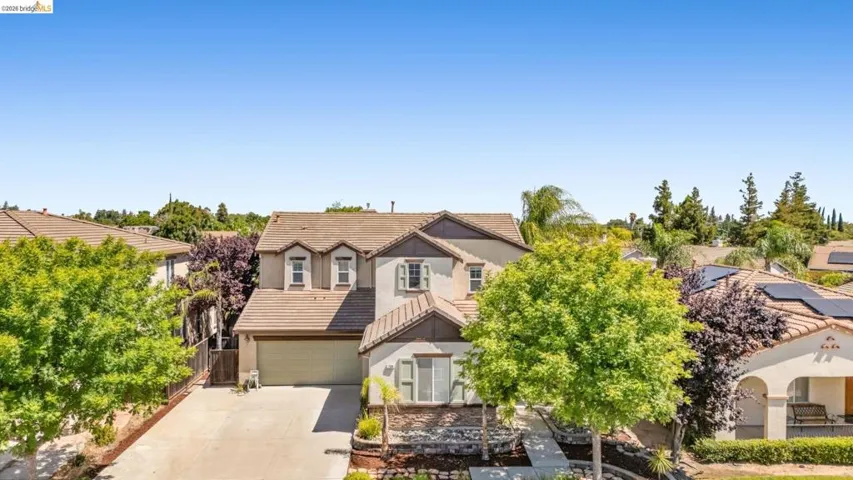 Two-story residence featuring a tile roof, light-colored stucco exterior, and a two-car garage