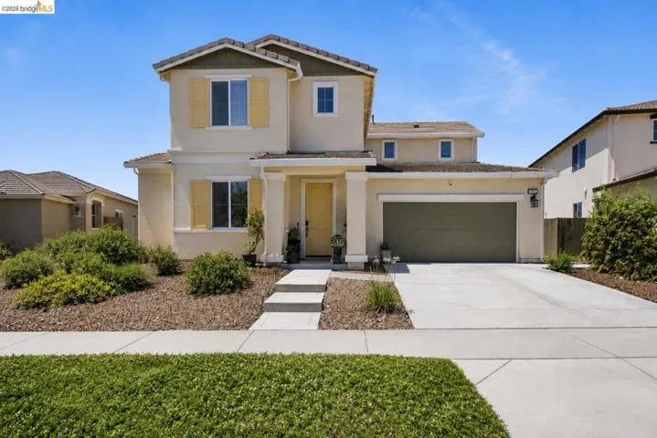 Two-story stucco exterior featuring a covered front entry, attached garage, and concrete driveway