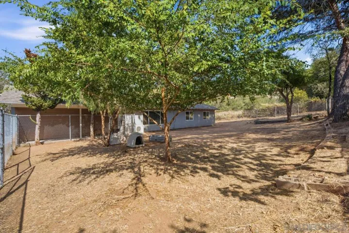 Front yard fenced and shady with trees.