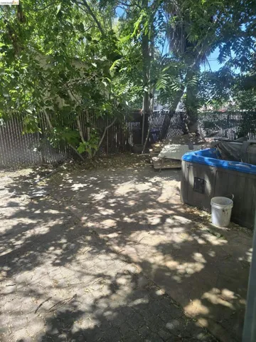 Private outdoor space featuring mature trees and a slatted wood fence