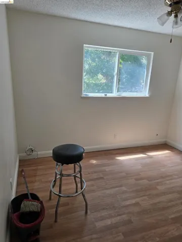 Bright interior room featuring wood-finish flooring, white baseboards, and a window providing natural light