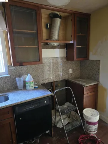 Kitchen area featuring base cabinets, upper cabinetry with glass-front doors, and stone countertops