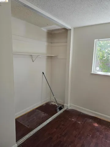 Closet space featuring a single shelf, overhead track for sliding doors, and wood-finish flooring