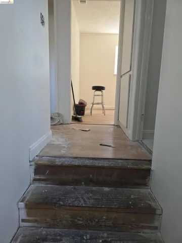 Two-step staircase with wood treads and white risers, framed by white walls