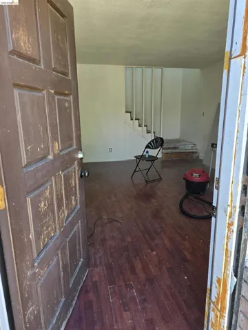 Entryway featuring wood-finish flooring, a paneled door, and a partially enclosed staircase
