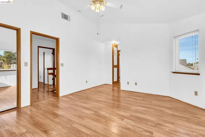 Spacious room featuring wood-finish flooring, vaulted ceiling, and a ceiling fan