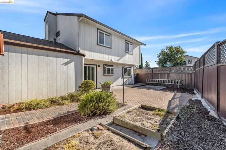 Rear exterior featuring a paver patio, wood fencing, and a side access pathway