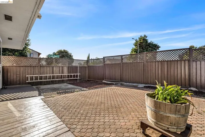 Outdoor patio featuring brick pavers, a wood deck section, and a wood privacy fence with lattice accents