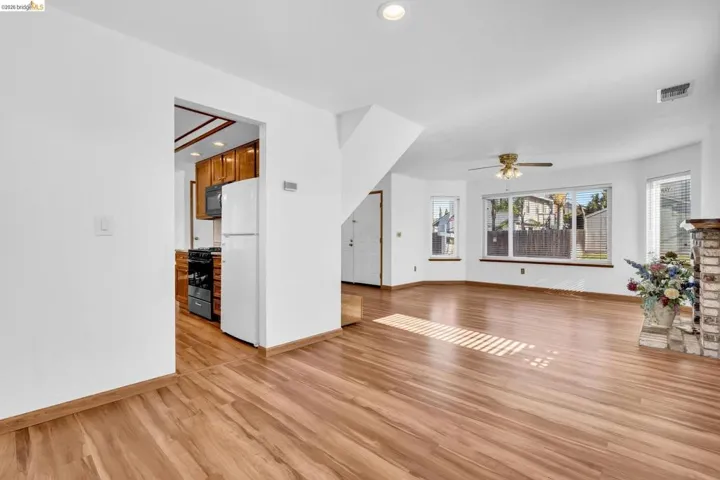 Open concept living area with wood-finish flooring, a brick fireplace, and multiple windows