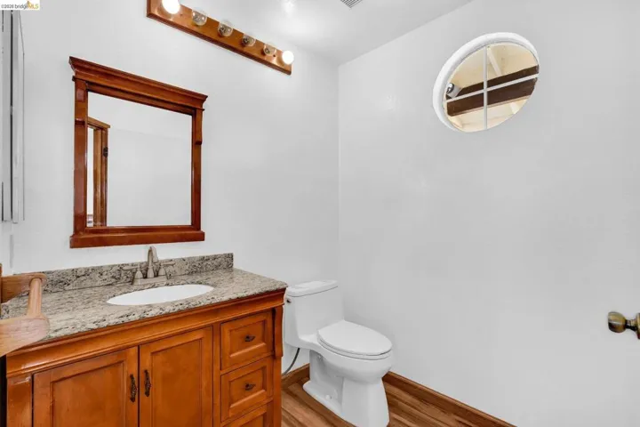 Bathroom featuring a wood-finish vanity with a granite countertop, undermount sink, and chrome faucet
