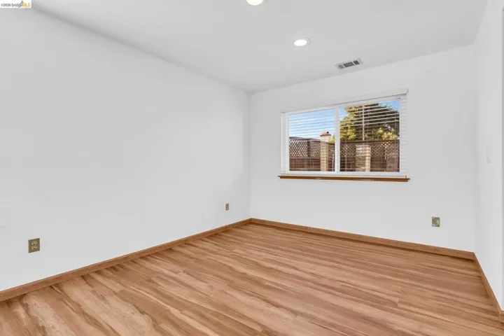 Bright room featuring wood-finish flooring, recessed lighting, and a window with horizontal blinds