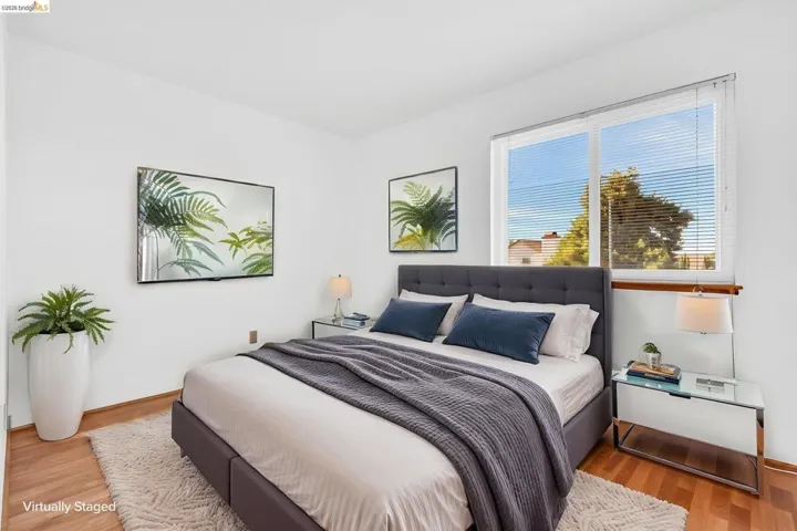 Bright room featuring wood-finish flooring and a large window with horizontal blinds