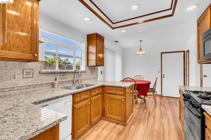 Kitchen featuring granite countertops, wood-finish flooring, recessed lighting, and a decorative tray ceiling