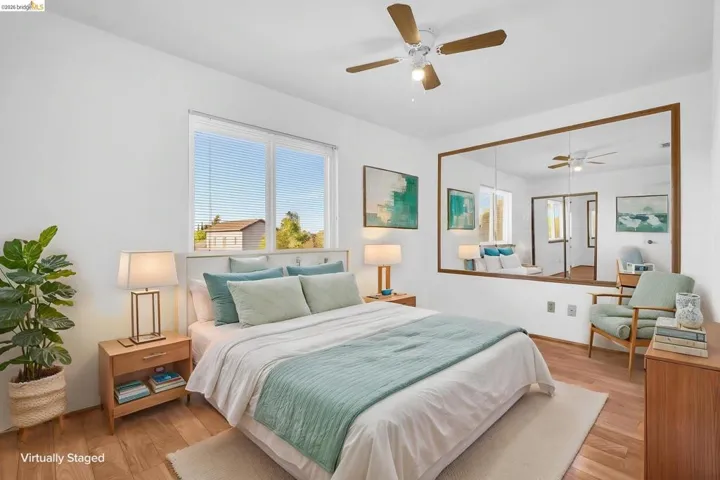 Bright room featuring wood-finish flooring, a large window with horizontal blinds, and a ceiling fan with integrated lighting