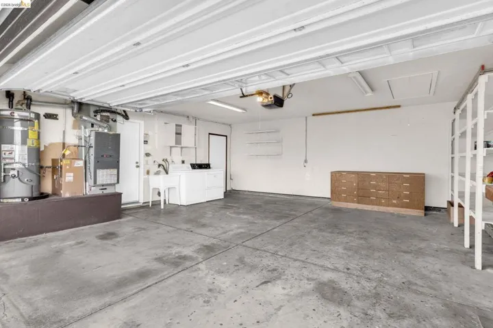 Spacious garage featuring a concrete floor, built-in cabinetry, overhead lighting, and dedicated laundry hookups with a utility sink