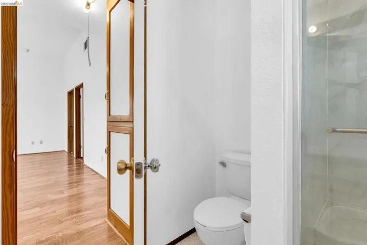 Bathroom featuring a white toilet and a glass-enclosed shower with a polished chrome grab bar