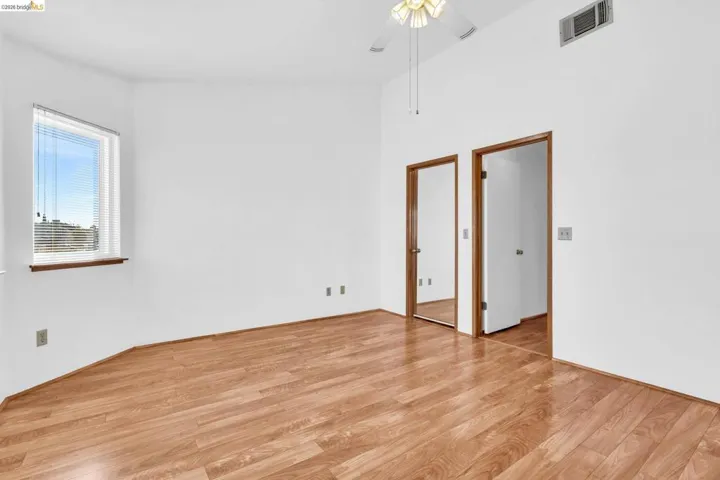 Bright room featuring wood-finish flooring, a vaulted ceiling, and a ceiling fan