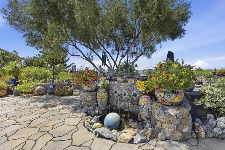 A calming water feature with gently cascading water flowing over stone surrounded by greenery creating a tranquil retreat.