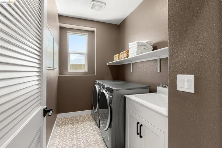 Laundry area with washing machine and clothes dryer and light tile patterned flooring